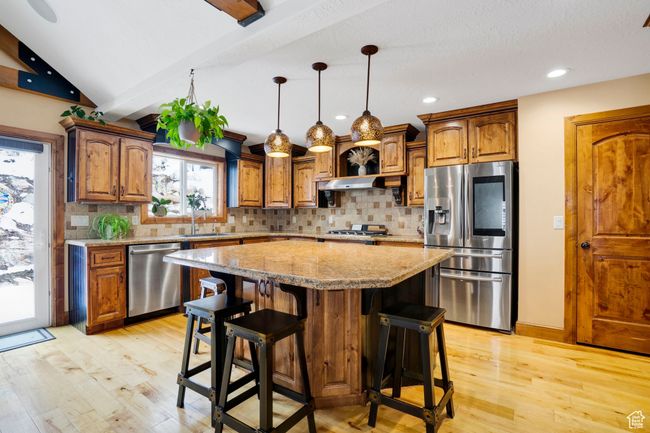 Kitchen featuring lofted ceiling with beams, a sink, stainless steel appliances, and light wood finished floors | Image 12