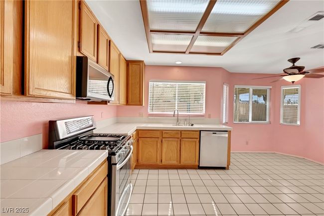 Kitchen with tile countertops, plenty of natural light, stainless steel appliances, and a sink | Image 8