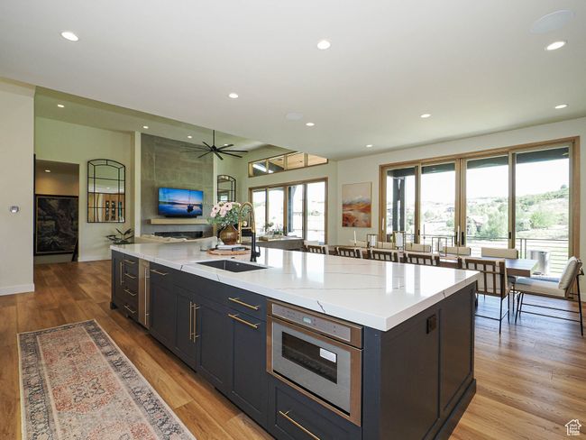 Kitchen featuring light wood-style floors, open floor plan, recessed lighting, a large island with sink, and a ceiling fan | Image 33