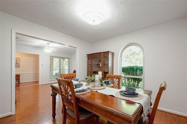 This inviting dining room features an arched window offering a view of the front yard. The space connects seamlessly to the kitchen with hardwood floors and ample natural light. | Image 13