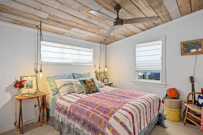 Bedroom featuring wooden ceiling, lofted ceiling, concrete flooring, and a ceiling fan | Image 17