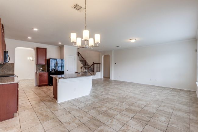 Kitchen with tasteful backsplash, black appliances, arched walkways, and a chandelier | Image 7