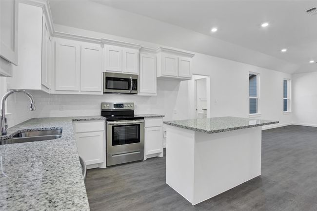 Kitchen featuring appliances with stainless steel finishes, a sink, white cabinetry, and recessed lighting | Image 6