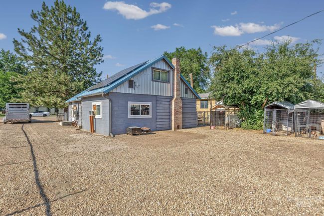 Rear view of property featuring concrete block siding, a chimney, solar panels, and an outbuilding | Image 17