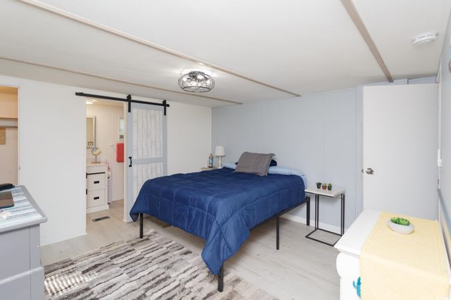 Bedroom featuring light wood-type flooring and a barn door | Image 18