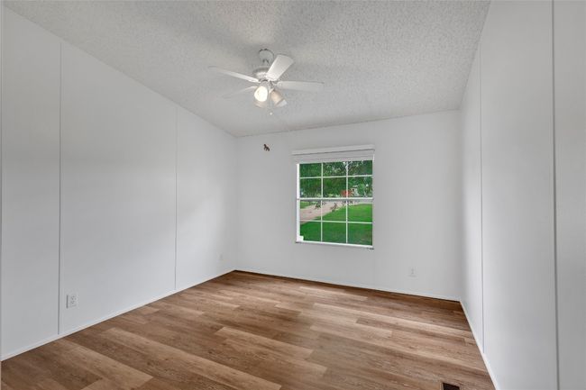 Empty room with a textured ceiling, ceiling fan, and wood finished floors | Image 20
