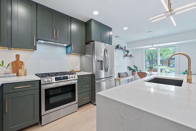 Kitchen featuring stainless steel appliances, custom range hood, tasteful backsplash, light wood finished floors, and recessed lighting | Image 12