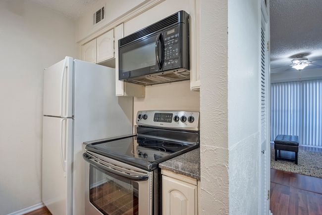 A kitchen featuring a range, microwave oven and a refrigerator, showcasing a modern and functional cooking space. | Image 13