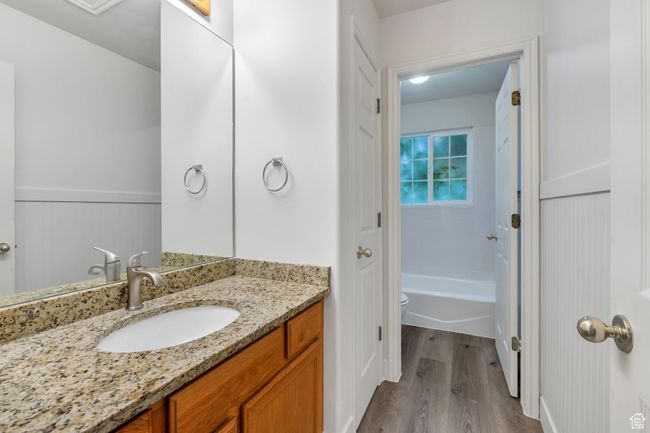 Full bath with wood finished floors, vanity, wainscoting, and toilet | Image 12