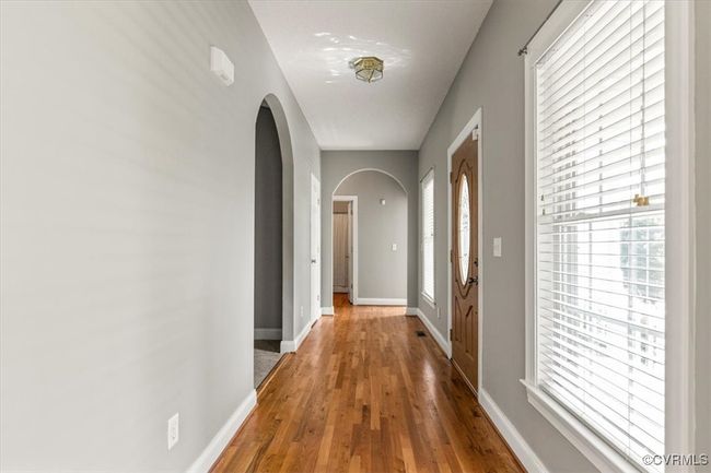 Hallway with arched walkways, wood finished floors, baseboards, and plenty of natural light | Image 5