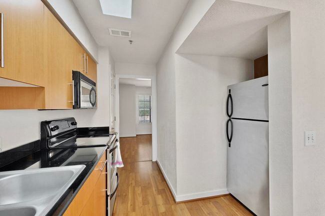 Kitchen featuring appliances with stainless steel finishes, light wood finished floors, light brown cabinets, and modern cabinets | Image 6