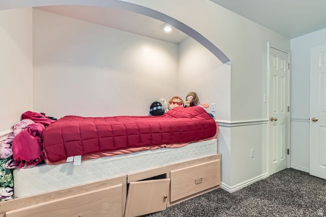Bedroom featuring arched walkways and dark colored carpet | Image 23