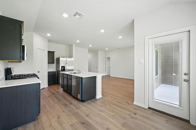 Kitchen with stainless steel appliances, light countertops, light wood finished floors, a kitchen island with sink, and recessed lighting | Image 6