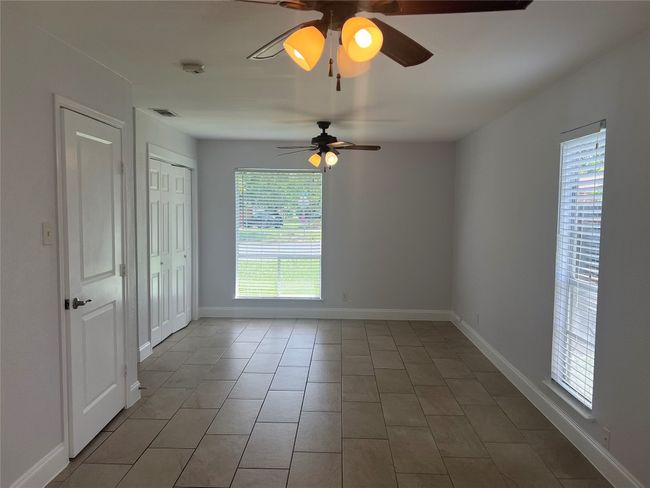 Tiled empty room with ceiling fan, plenty of natural light, and a smoke detector | Image 10