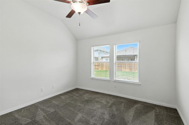 Unfurnished room featuring dark colored carpet, lofted ceiling, and a ceiling fan | Image 25