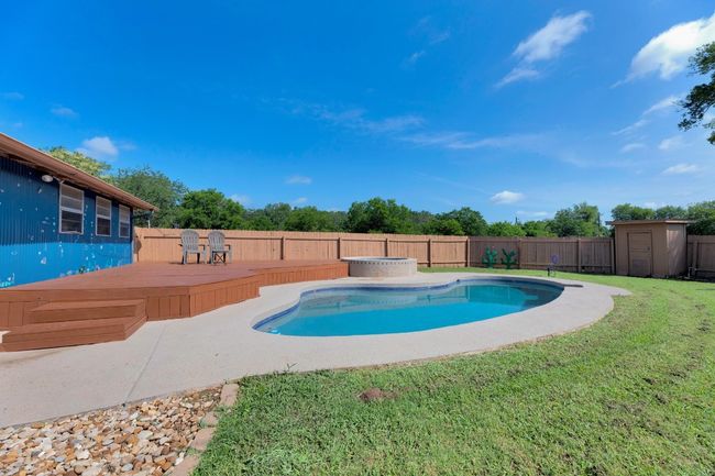 View of swimming pool with a wooden deck, a fenced backyard, and a shed | Image 28