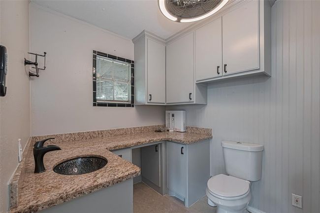 Primary en suite bathroom with granite countertops, brass bowl sink, and plenty of cabinet storage. | Image 25