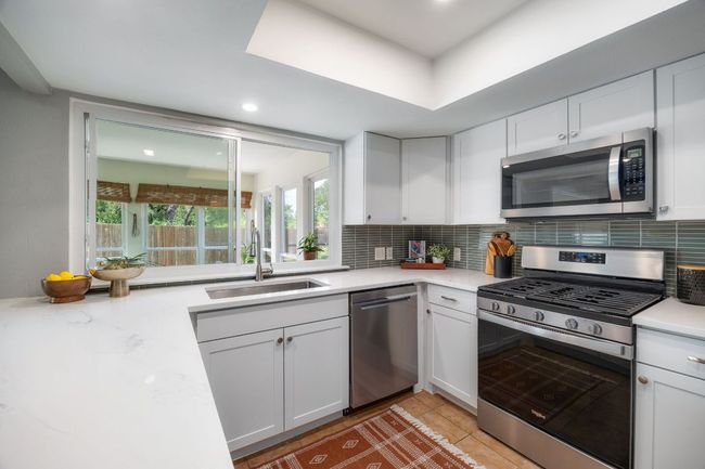 Kitchen opens to sunroom through a window, making entertaining easy | Image 10