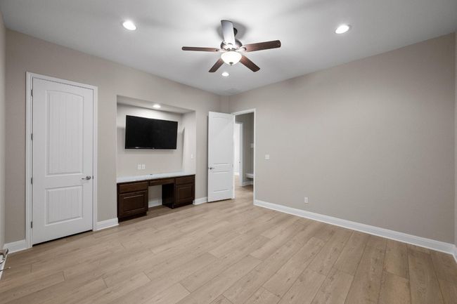 Unfurnished bedroom with light wood-type flooring, built in study area, recessed lighting, and ceiling fan | Image 17