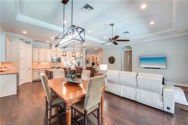 Dining space with a raised ceiling, crown molding, arched walkways, dark wood-style floors, and recessed lighting | Image 15