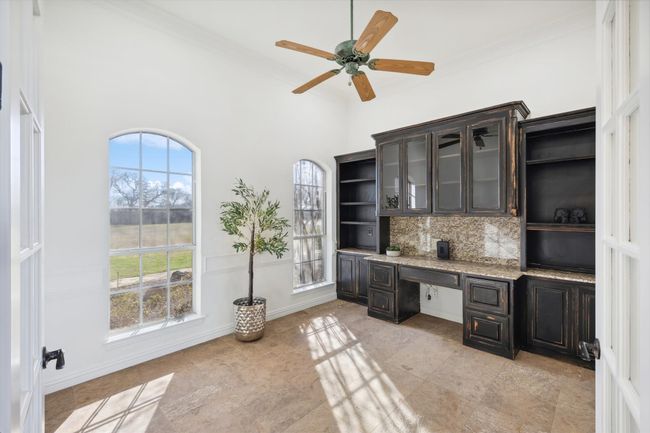 Unfurnished office with crown molding, ceiling fan, built in study area, and a high ceiling | Image 5