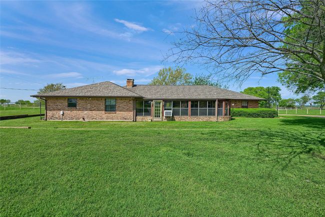 View of front of home with a chimney, a front yard, brick siding, a sunroom, and fence | Image 33