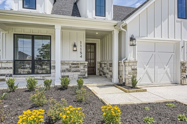 View of exterior entry featuring board and batten siding, roof with shingles, covered porch, and stone siding | Image 4