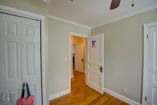 Unfurnished bedroom with a closet, baseboards, crown molding, and light wood finished floors | Image 23