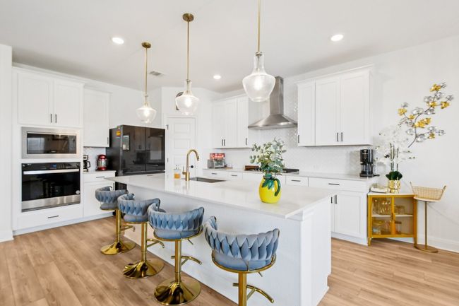 Kitchen with wall chimney range hood, stainless steel oven, built in microwave, freestanding refrigerator, and backsplash | Image 7