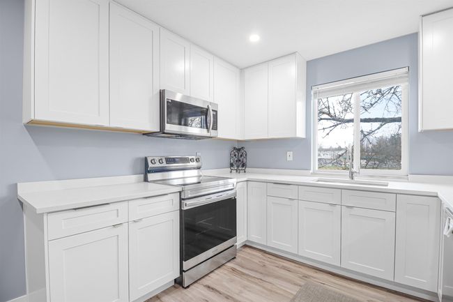Kitchen with a sink, white cabinetry, light countertops, and appliances with stainless steel finishes | Image 8