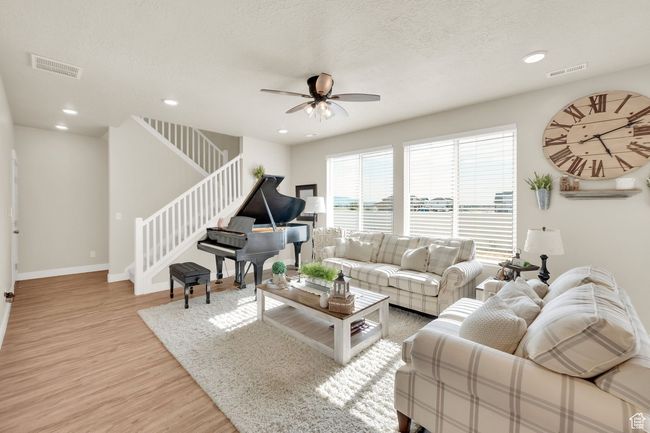 Living area featuring light wood-style floors, ceiling fan, stairs, recessed lighting, and baseboards | Image 6