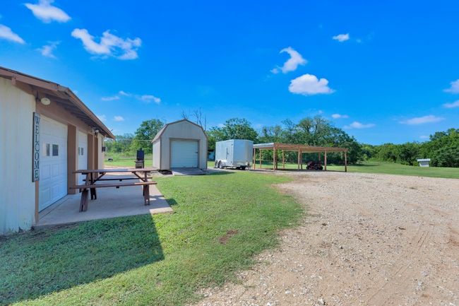 View of green lawn featuring an outdoor structure and a detached carport | Image 7