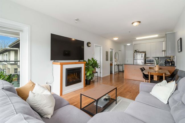 Living room featuring light wood-style flooring, baseboards, and a glass covered fireplace | Image 10