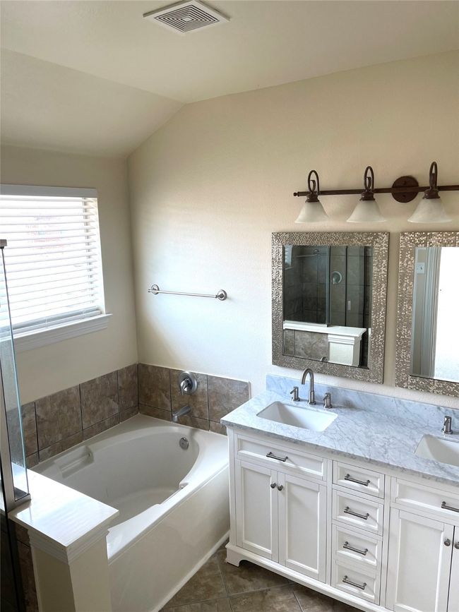 Bathroom featuring a bath, double vanity, vaulted ceiling, and tile patterned flooring | Image 17
