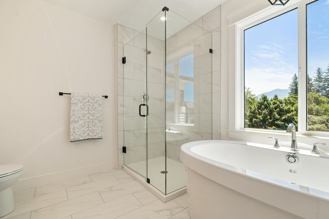 Bathroom featuring marble look tiles, a freestanding tub, and a stall shower | Image 22