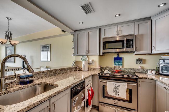 Kitchen with appliances with stainless steel finishes, a sink, gray cabinets, decorative light fixtures, and light stone counters | Image 4