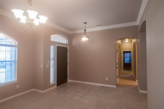 Foyer entrance with light colored carpet, arched walkways, ornamental molding, baseboards, and a chandelier | Image 10