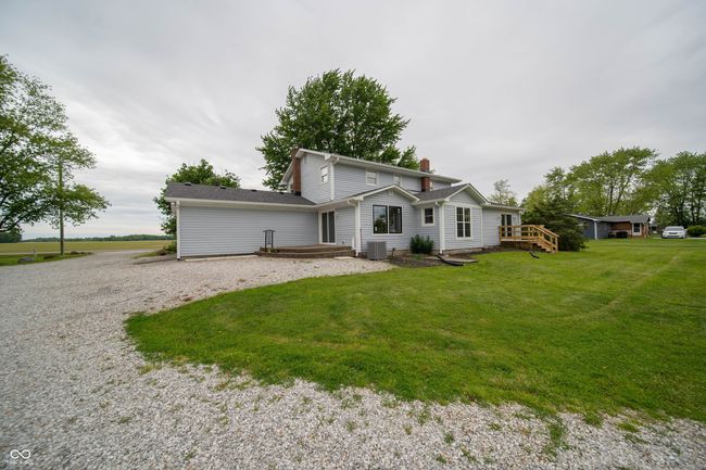 view of front of property featuring a front lawn, cooling unit, a chimney, gravel driveway, and a wooden deck | Image 43