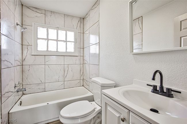 Bathroom featuring a textured wall, vanity, and shower / bath combination | Image 16