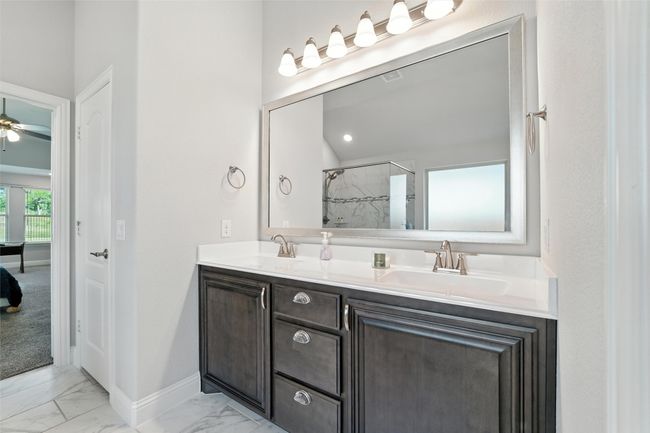 Full bathroom with marble look tiles, double vanity, a shower, and ceiling fan | Image 23