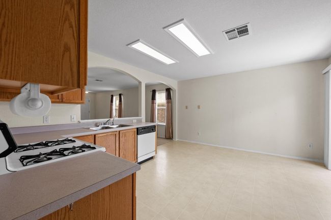 Kitchen featuring white dishwasher, a sink, arched walkways, light countertops, and range with gas cooktop | Image 12