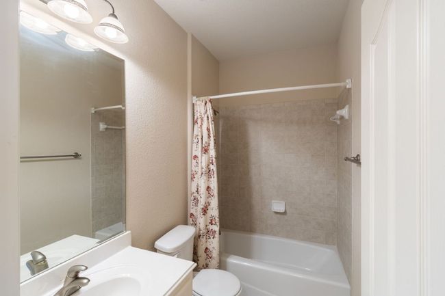 Bathroom featuring vanity, toilet, shower / bath combo with shower curtain, and a textured wall | Image 34