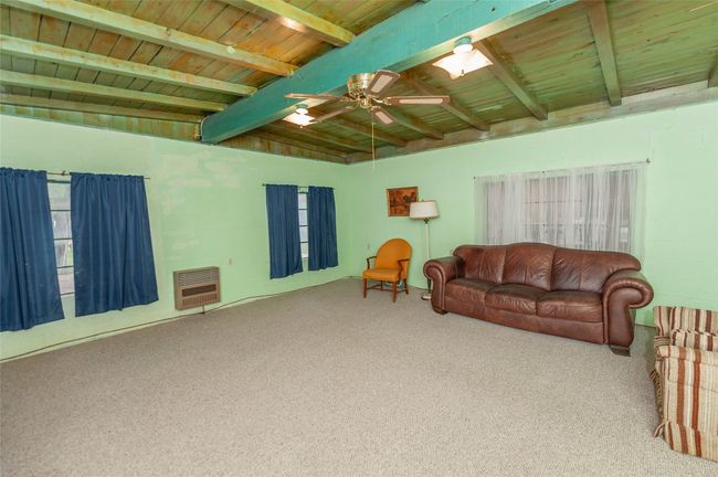 Living area featuring carpet flooring, wood ceiling, a ceiling fan, and heating unit | Image 13