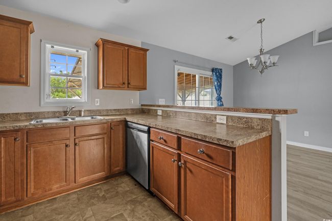 Kitchen featuring dishwasher, a sink, a peninsula, brown cabinets, and vaulted ceiling | Image 21