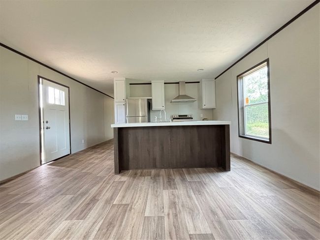Kitchen featuring white cabinetry, light countertops, light wood-style flooring, exhaust hood, and ornamental molding | Image 6
