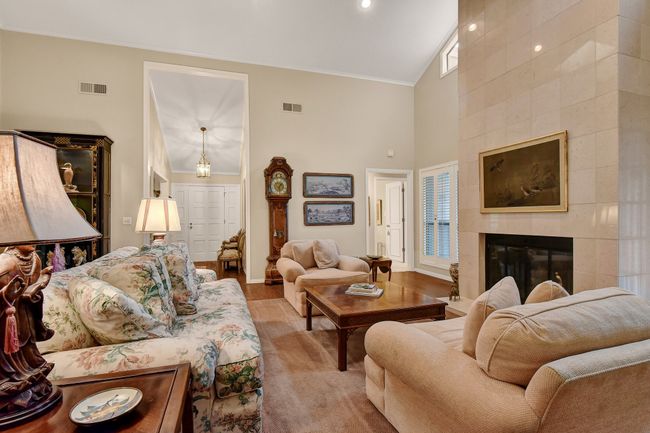 Living area with high vaulted ceiling, crown molding, a tiled fireplace, and baseboards | Image 11