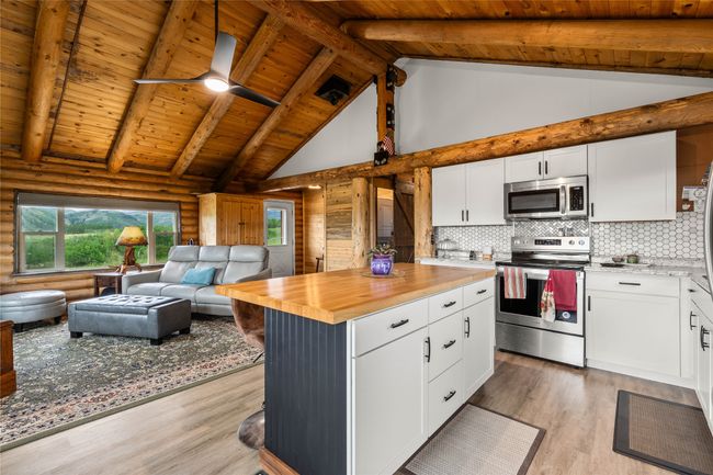 Kitchen featuring appliances with stainless steel finishes, open floor plan, a wood ceiling with exposed beams, butcher block countertops, and log walls | Image 9