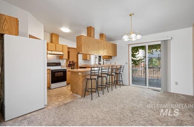 Kitchen with white appliances, vaulted ceiling, a chandelier, a peninsula, and a breakfast bar area | Image 5