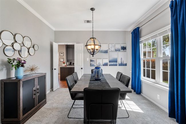 Carpeted dining area with a notable chandelier, crown molding, baseboards, and visible vents | Image 6