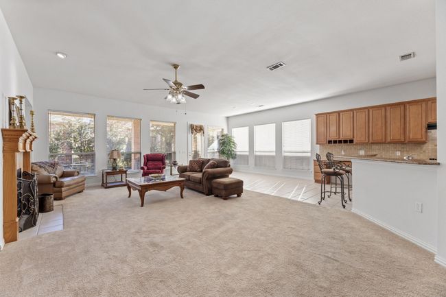Carpeted living room with ceiling fan, a brick fireplace, and plenty of natural light | Image 11